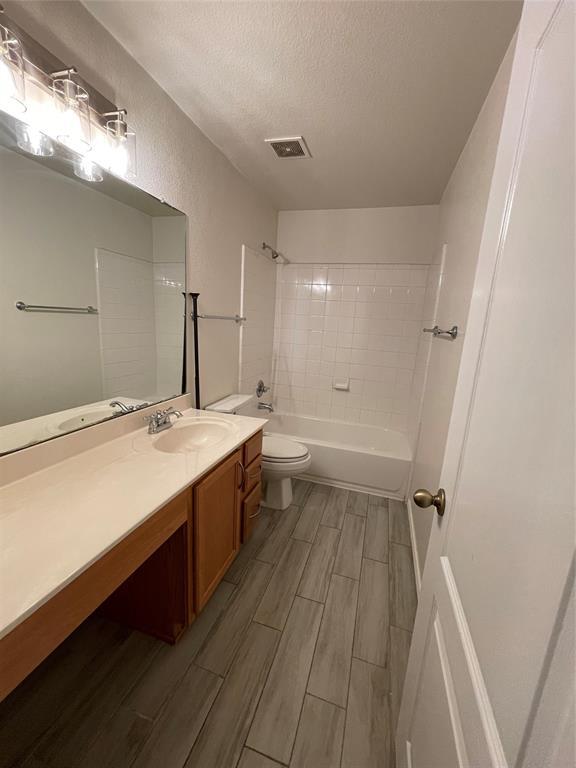 904 Watson Way Pflugerville, TX 78660 - Photo 15 of 16 Bathroom with tub / shower combination, vanity, wood finish floors, and a textured ceiling