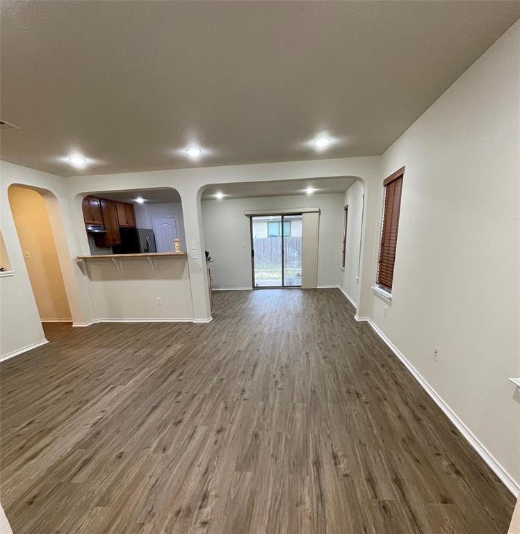 904 Watson Way Pflugerville, TX 78660 - Photo 5 of 16 Unfurnished living room featuring arched walkways, dark wood-style floors, and recessed lighting
