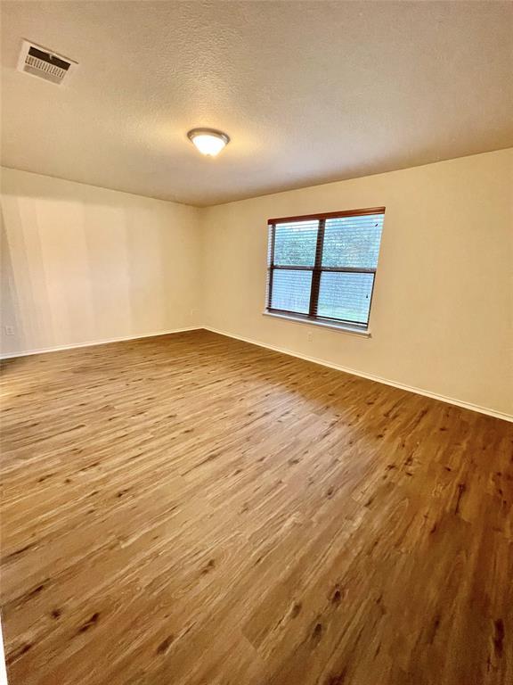 904 Watson Way Pflugerville, TX 78660 - Photo 9 of 16 Unfurnished room featuring a textured ceiling and light wood-style flooring