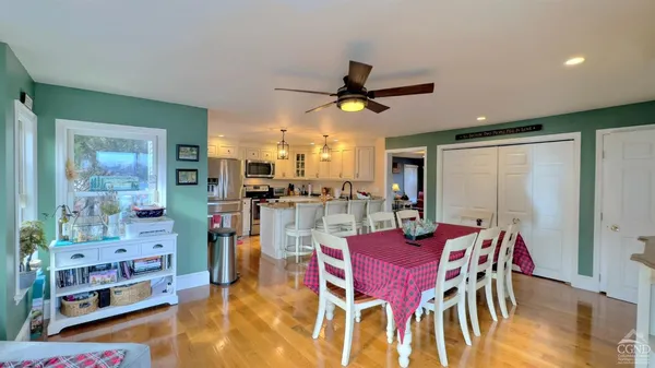 a dining room with stainless steel appliances kitchen island granite countertop a dining table and chairs with wooden floor