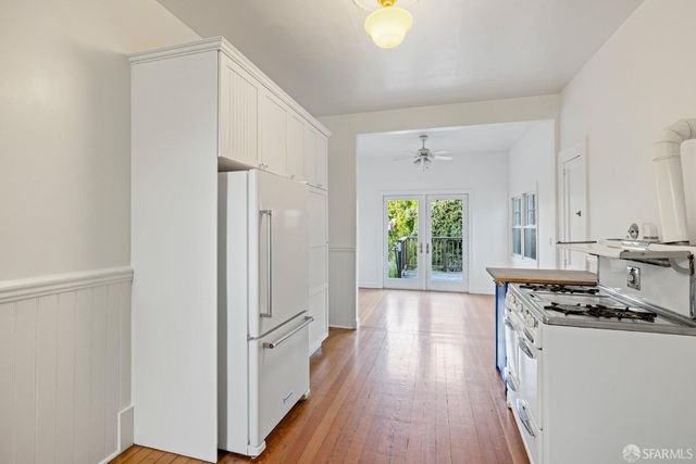 a kitchen with stainless steel appliances a stove a sink dishwasher and white cabinets with wooden floor