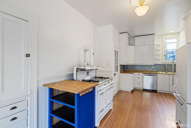an empty room with wooden floor fireplace and windows