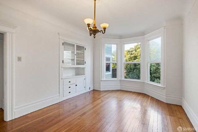 a view of a room with wooden floor chandelier and windows