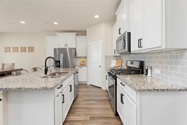 a kitchen with stainless steel appliances white cabinets and wooden floor