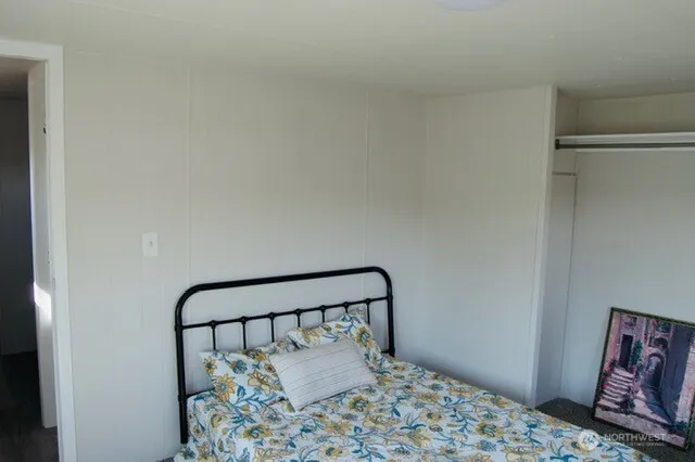 a bedroom with a bed and a lamp on dresser