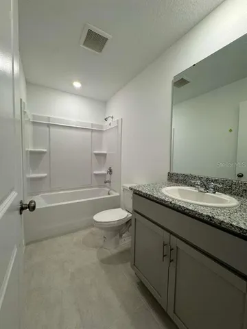 a bathroom with a granite countertop sink a toilet and shower