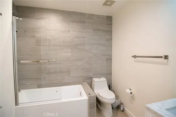 a white toilet sitting next to a bath tub and a shower