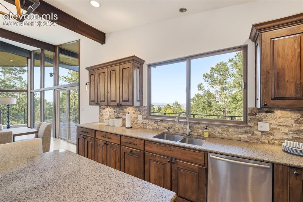 17 Pine Road Colorado Springs, CO 80906 - Photo 19 of 48 Kitchen featuring wood cabinetry, granite countertops, stainless steel appliances, and a stone-finish backsplash