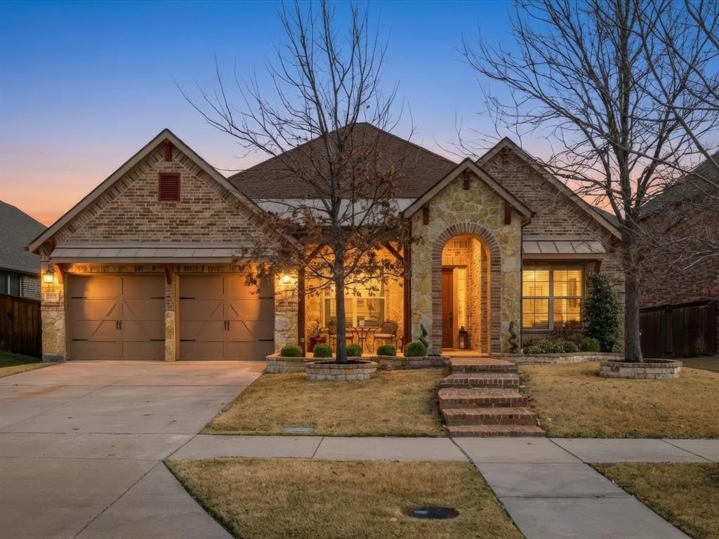 View of front of home featuring stone siding, driveway, and a garage