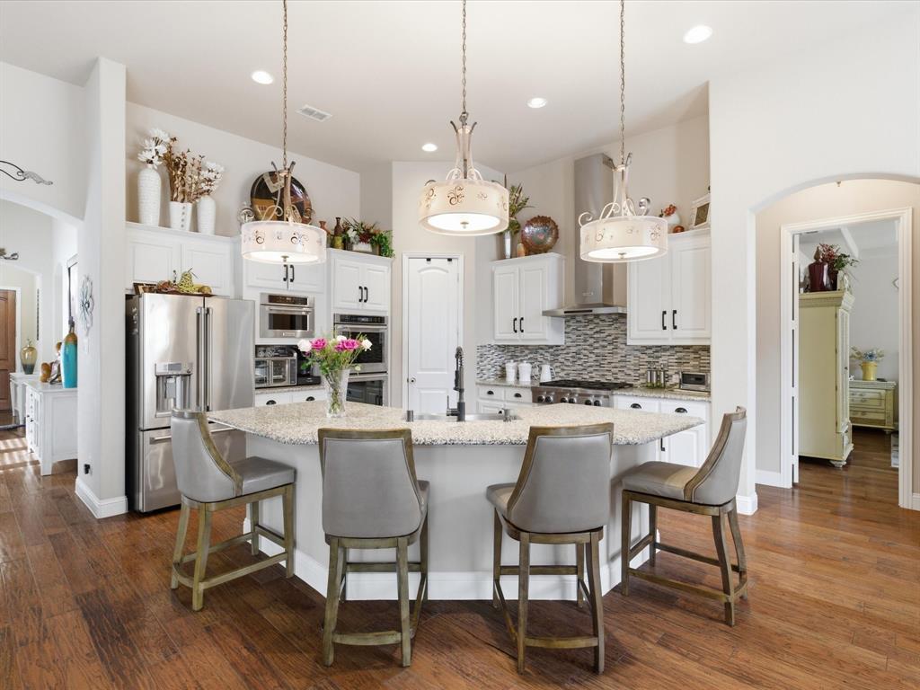 13788 El Toro Road Frisco, TX 75035 - Photo 11 of 29 Kitchen with arched walkways, white cabinetry, stainless steel appliances, pendant lighting, and decorative backsplash