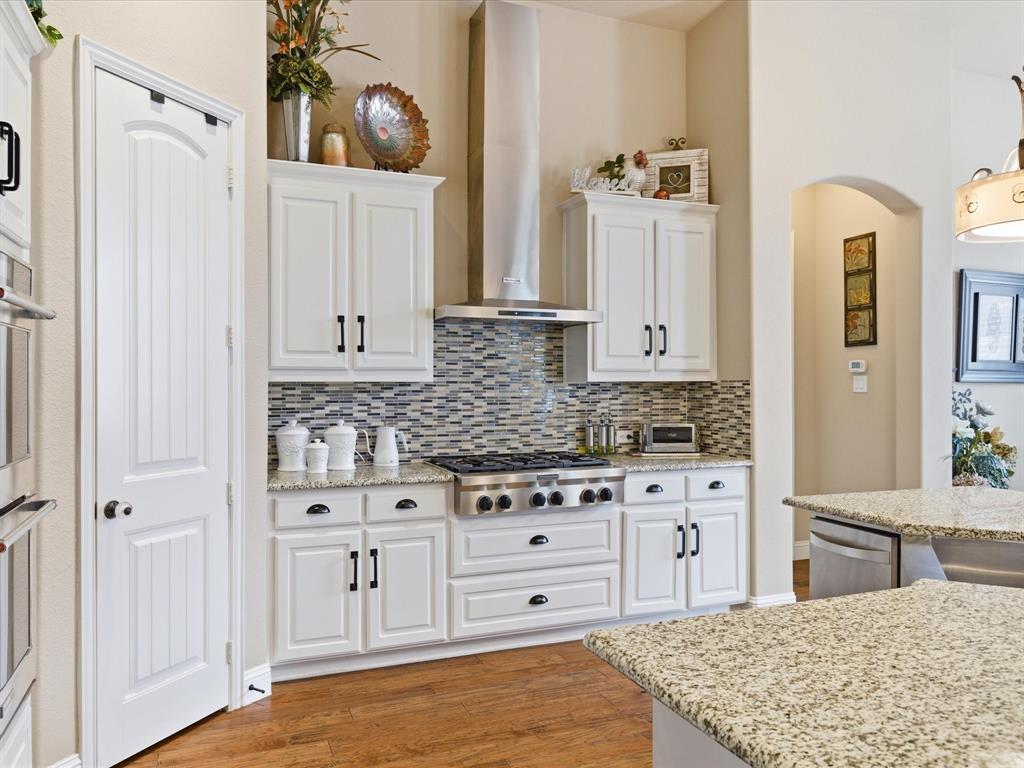 13788 El Toro Road Frisco, TX 75035 - Photo 12 of 29 Kitchen featuring white cabinetry, light stone countertops, light wood-type flooring, and stainless steel appliances