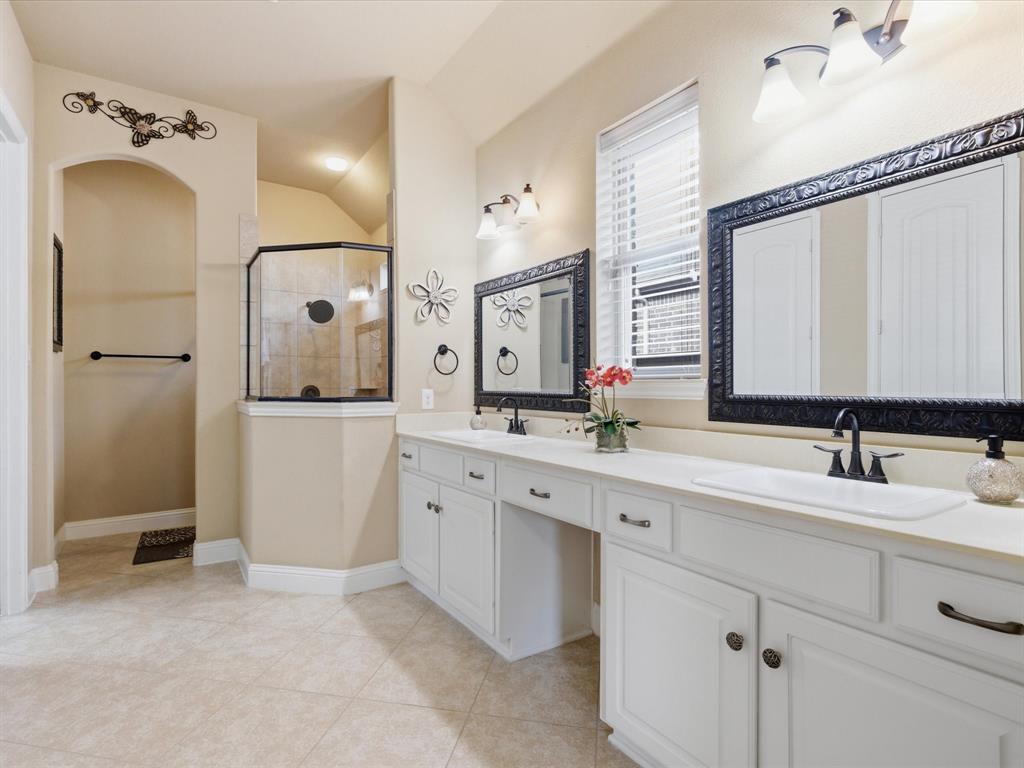 13788 El Toro Road Frisco, TX 75035 - Photo 17 of 29 Bathroom with double vanity, tiled shower, light tile patterned flooring, and lofted ceiling