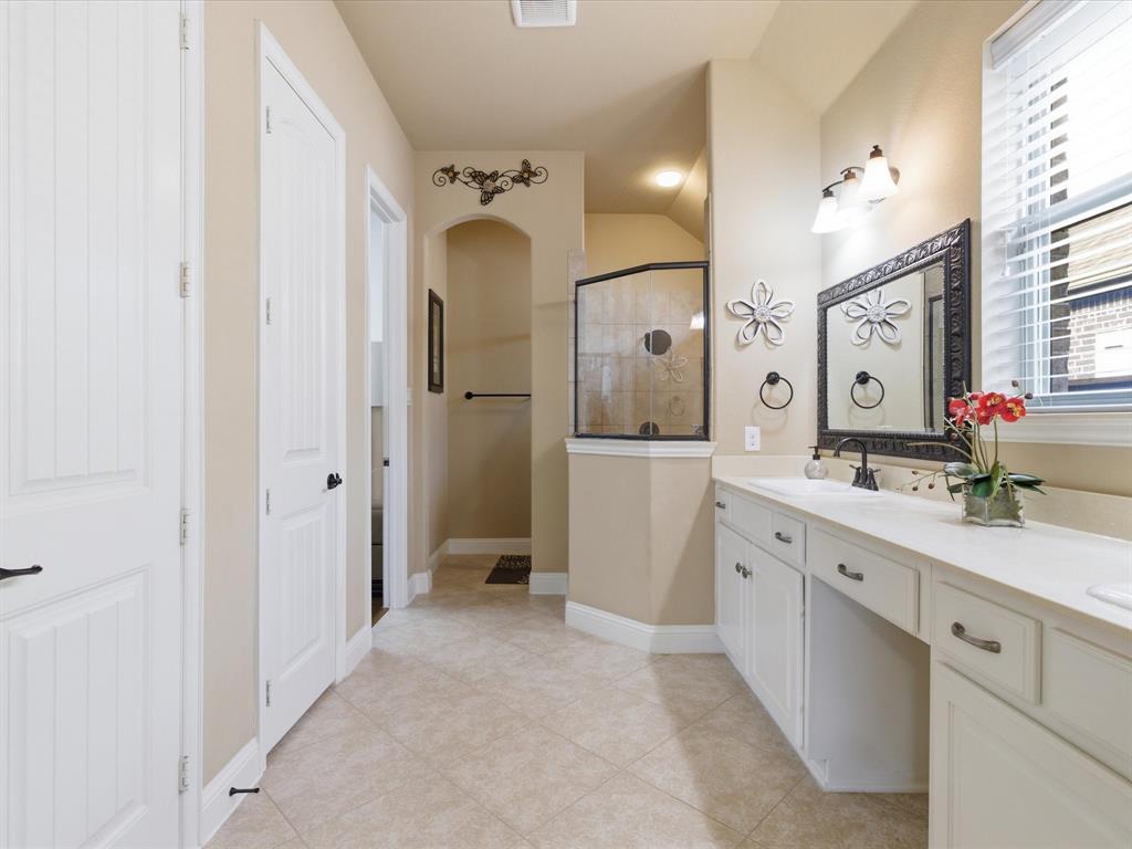 13788 El Toro Road Frisco, TX 75035 - Photo 18 of 29 Bathroom featuring double vanity, walk in shower, lofted ceiling, and light tile patterned flooring