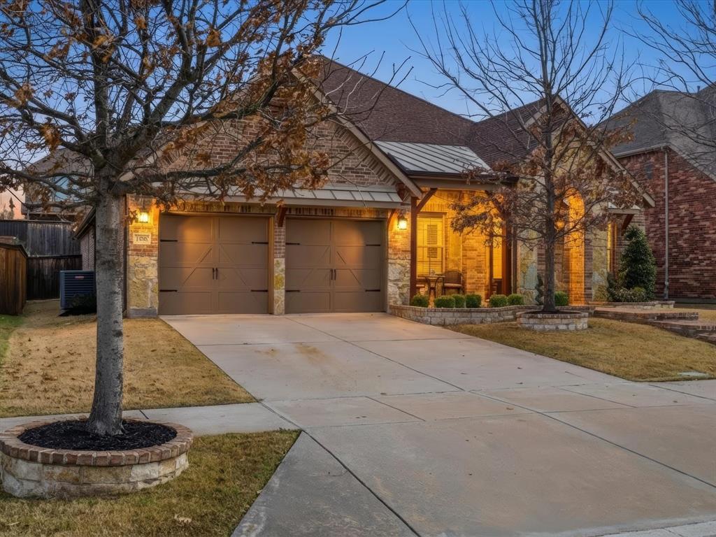 13788 El Toro Road Frisco, TX 75035 - Photo 2 of 29 View of front facade featuring stone siding, a standing seam roof, driveway, and an attached garage