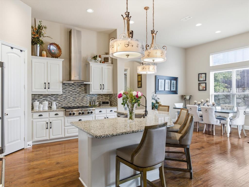 13788 El Toro Road Frisco, TX 75035 - Photo 10 of 29 Kitchen with a kitchen bar, hanging light fixtures, backsplash, white cabinets, and light stone countertops
