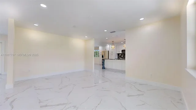 a kitchen with kitchen island granite countertop a stove a sink a refrigerator and white cabinets with wooden floor