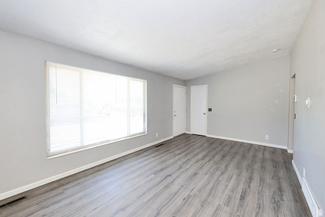 1272 Cook Street Ogden, UT 84404 - Photo 7 of 58 Spacious living area featuring light gray walls, wood-finish flooring, a large window with blinds, and white trim throughout