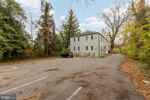 a view of a white house with a large tree next to a road