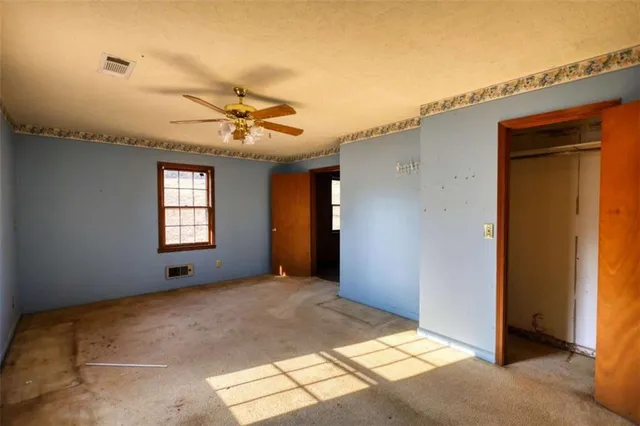 a view of a livingroom with a chandelier fan and windows