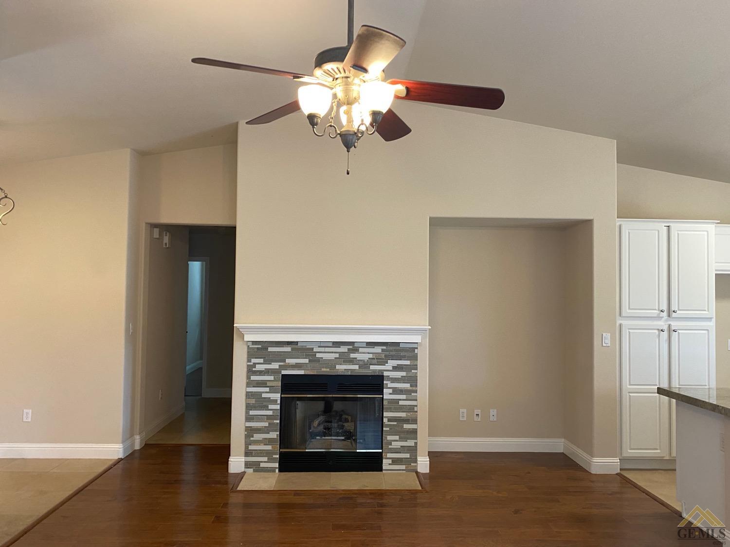 Undisclosed Address Bakersfield, CA 93311 - Photo 3 of 8 a view of a livingroom with a fireplace a chandelier and wooden floor
