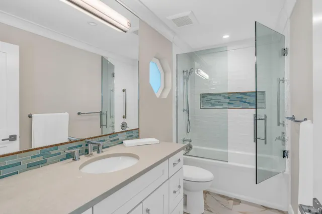 a bathroom with a sink a toilet a mirror and shower