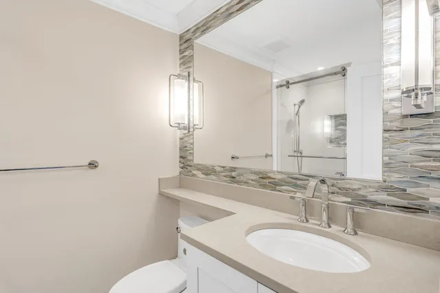 a bathroom with a sink toilet double vanity and a mirror