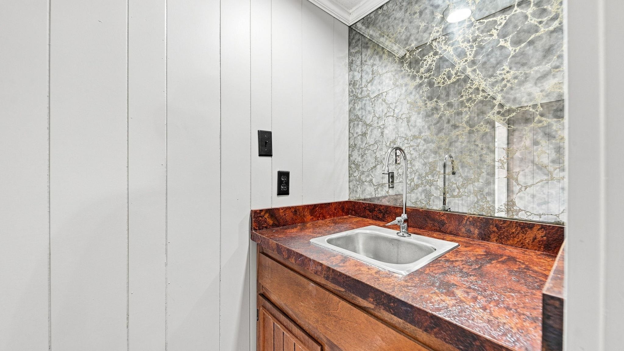 4920 Whitworth Road Memphis, TN 38116 - Photo 14 of 32 Wet bar with a stainless steel sink, a pull-down faucet, and a patterned mirror backsplash
