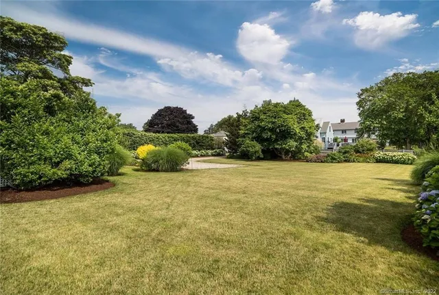 a view of a house with a big yard plants and large trees