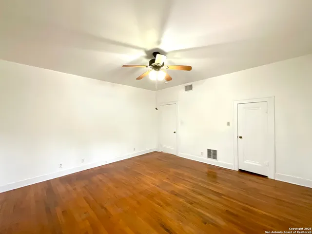 a view of an empty room with chandelier fan and a window