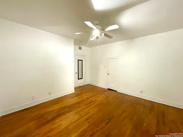 a view of an empty room with chandelier fan and a window
