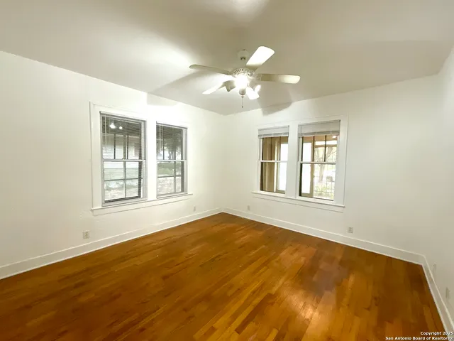 a view of an empty room with a window and wooden floor