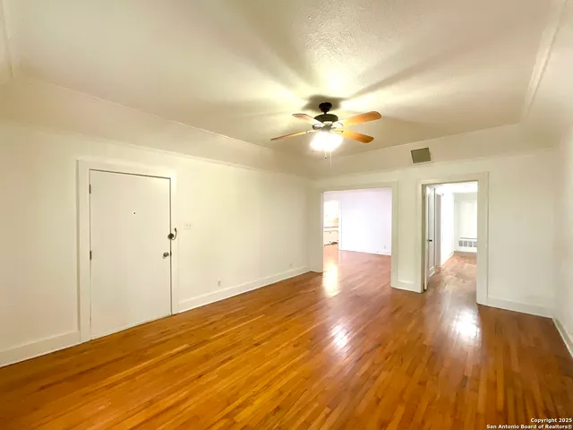 a view of an empty room with wooden floor and a window