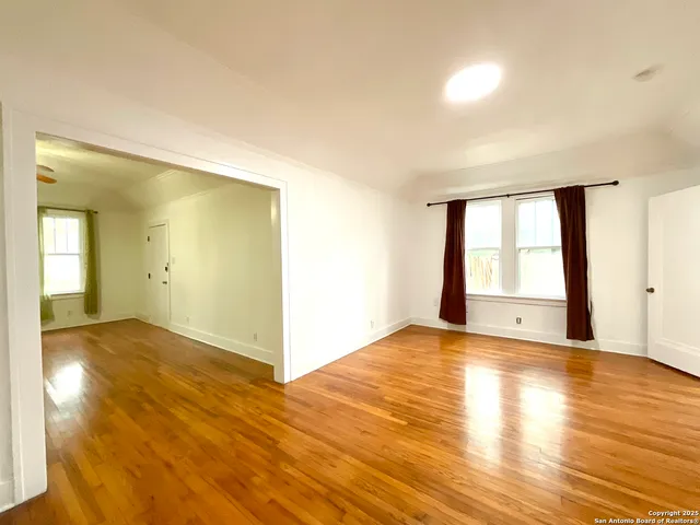 a view of an empty room with wooden floor and a window