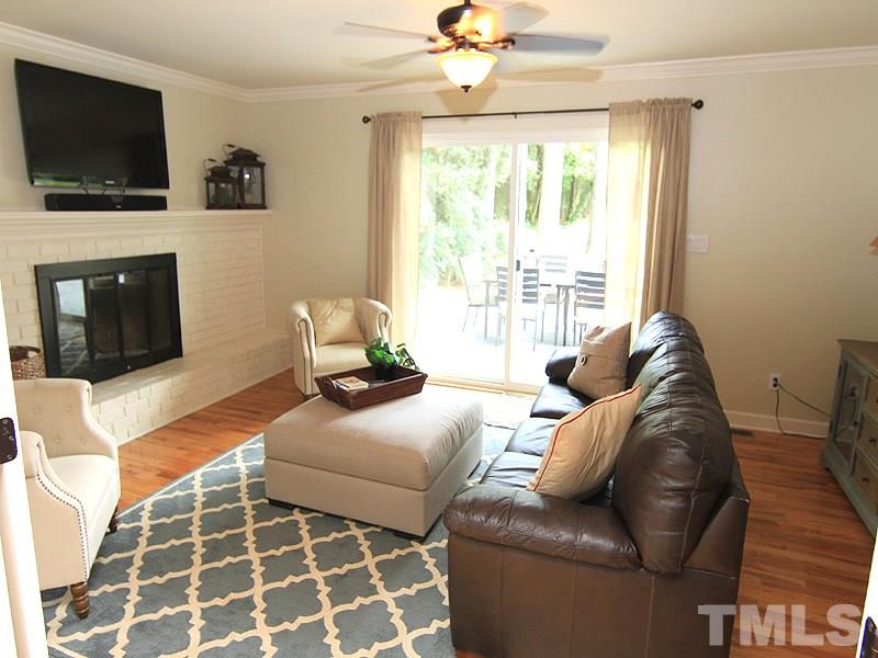 5016 Stonehill Drive Raleigh, NC 27609 - Photo 12 of 22 a living room with furniture a flat screen tv and a fireplace