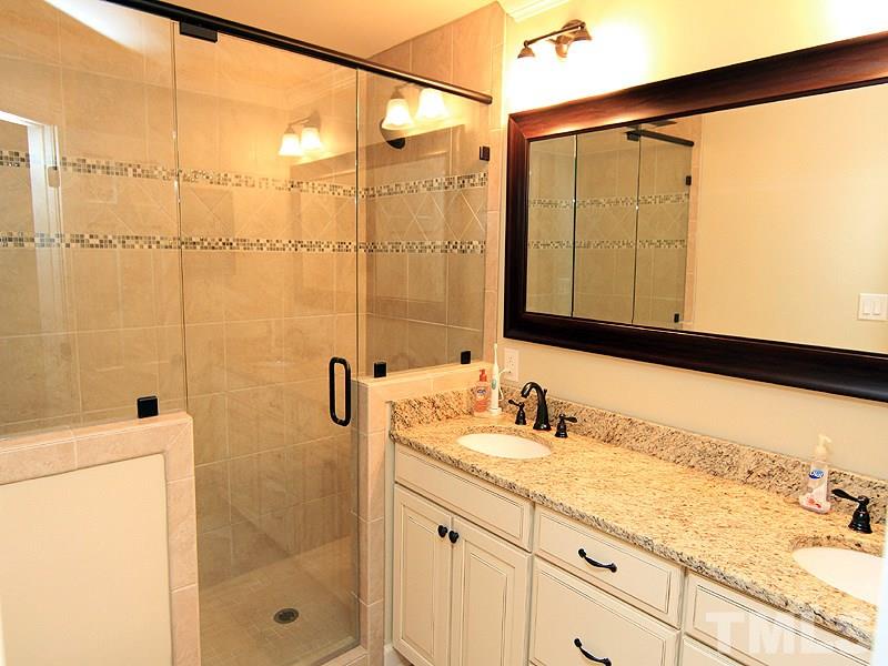 5016 Stonehill Drive Raleigh, NC 27609 - Photo 16 of 22 a bathroom with a granite countertop sink a mirror and shower
