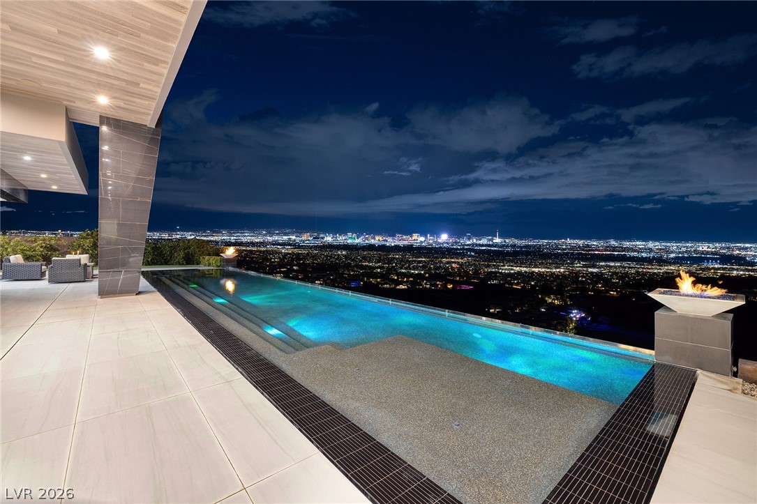 611 Cityview Ridge Drive Henderson, NV 89012 - Photo 2 of 66 An infinity pool looks out over sweeping city skyline views under a twilight sky.