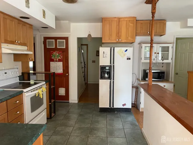 a kitchen with stainless steel appliances granite countertop a refrigerator a stove and a sink