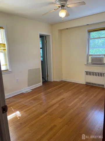 a view of an empty room with window and wooden floor