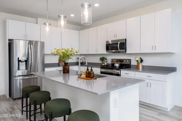 a kitchen with stainless steel appliances granite countertop a refrigerator a sink dishwasher a stove a microwave oven a sink with island and chairs