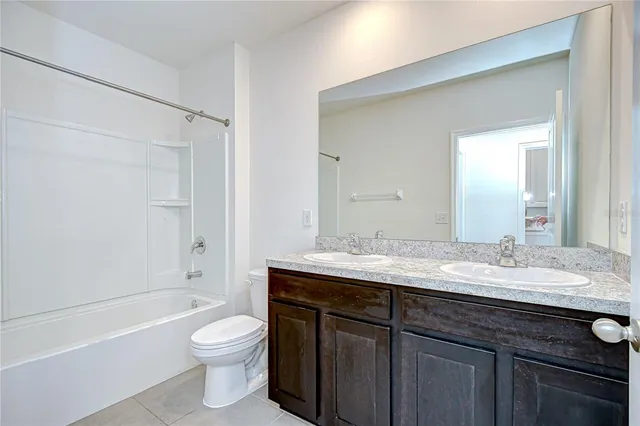 a bathroom with a granite countertop sink toilet a large mirror a bathtub and shower