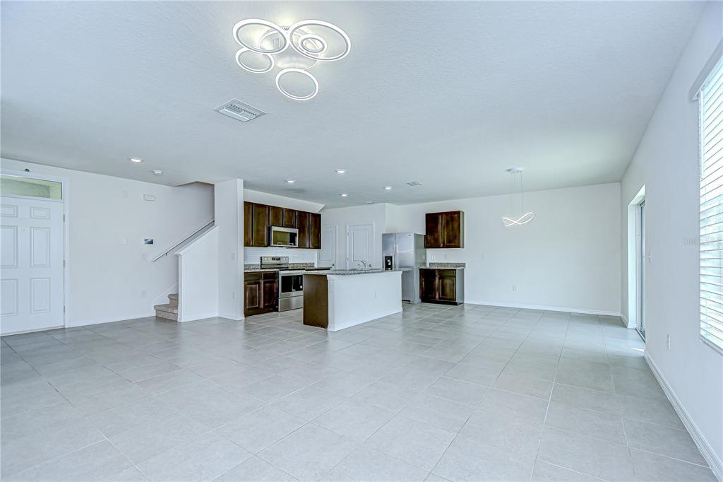 1382 Crescent Hoop Way Wesley Chapel, FL 33543 - Photo 8 of 27 an empty room with kitchen and refrigerator