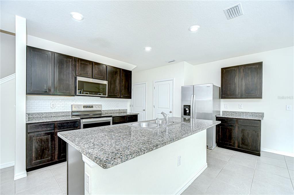 1382 Crescent Hoop Way Wesley Chapel, FL 33543 - Photo 9 of 27 a kitchen with stainless steel appliances granite countertop a sink dishwasher stove and oven