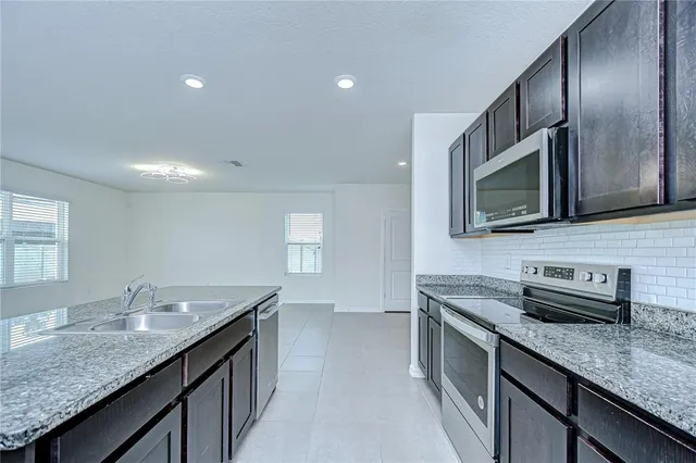 a kitchen with granite countertop stainless steel appliances a sink stove top oven and cabinets