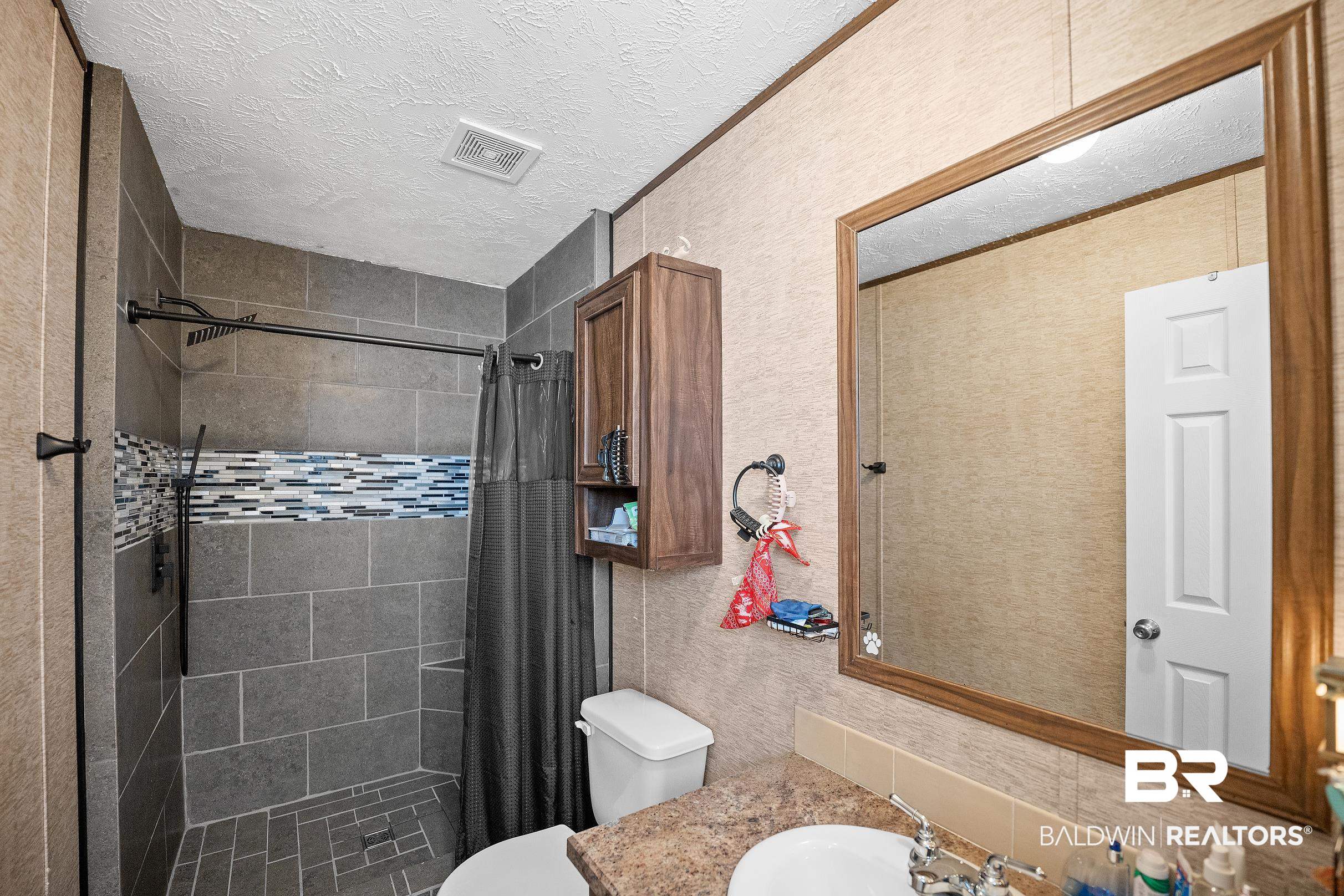 8630 Allison Lane Wilmer, AL 36587 - Photo 22 of 31 Bathroom featuring a shower stall, vanity, a textured ceiling, and a textured wall