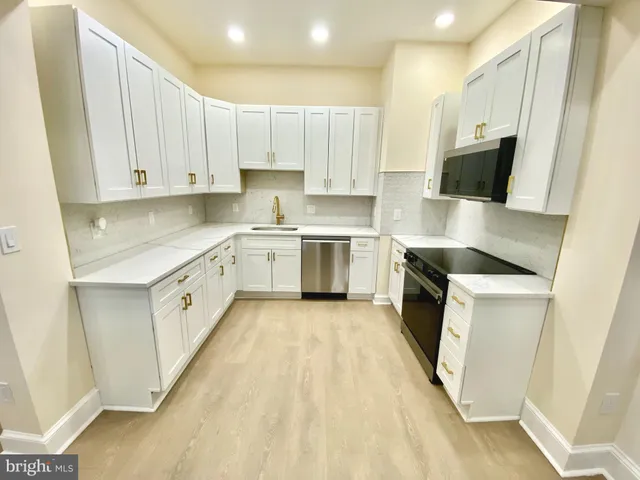 a kitchen with cabinets stainless steel appliances a sink and wooden floor