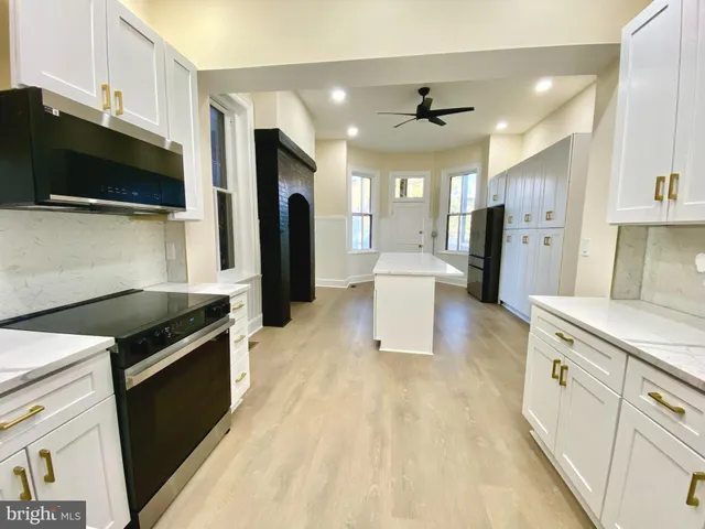 a kitchen with stainless steel appliances kitchen island granite countertop a refrigerator oven a sink dishwasher and white cabinets with wooden floor