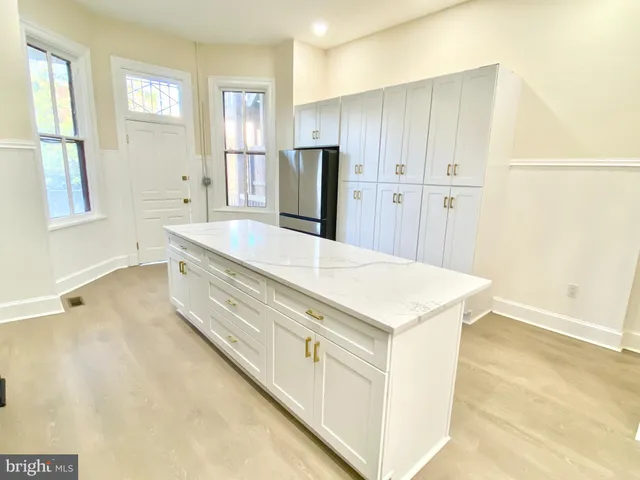 a large white kitchen with wooden floor