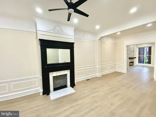 a view of an empty room with kitchen and fireplace