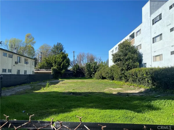a view of a white house in a big yard with large trees