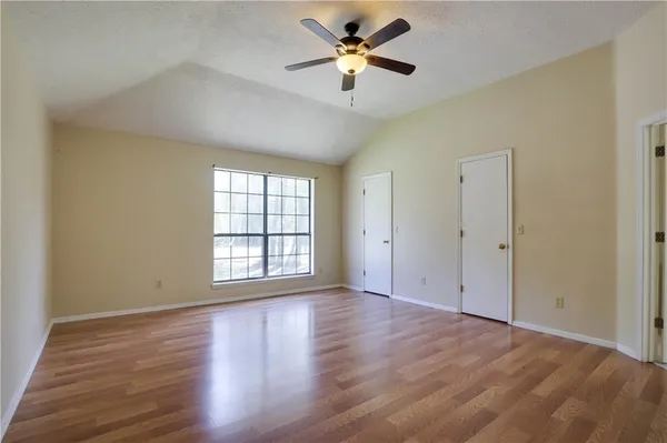 an empty room with wooden floor fan and windows